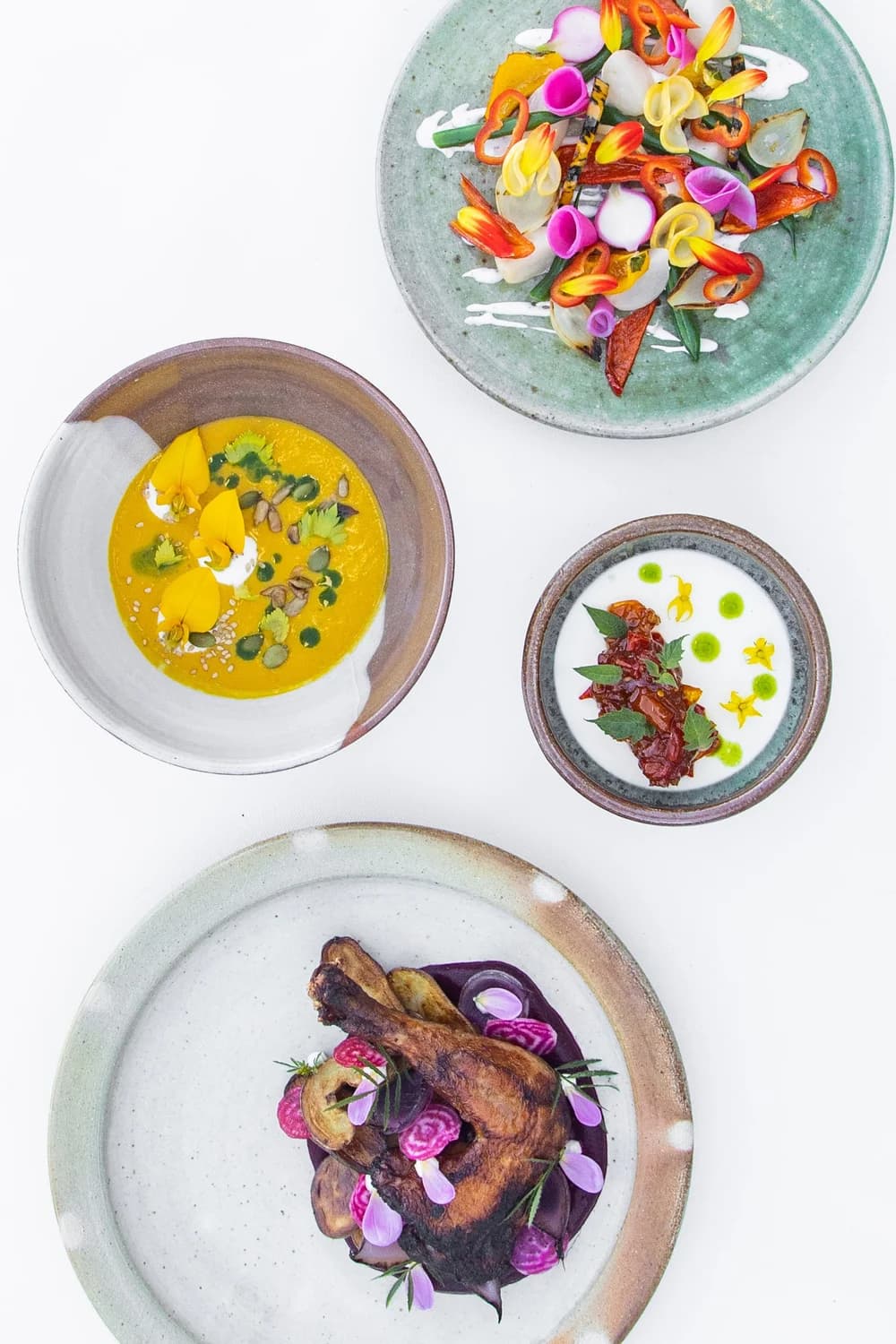Top-down view of four artfully plated dishes