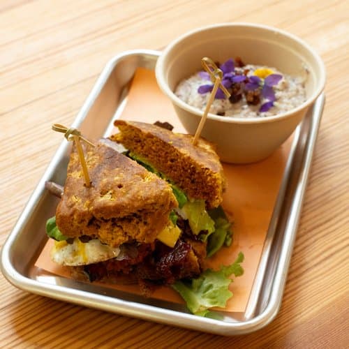 A farmhouse sandwich and dip served on a stainless tray