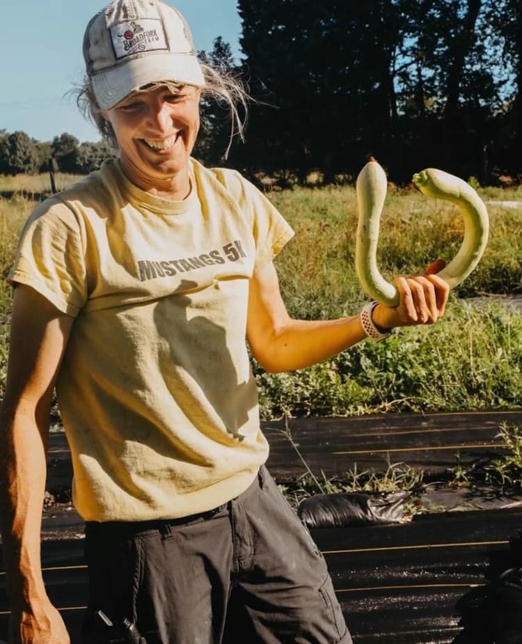 Karren, the head farmer, in the field holding squash