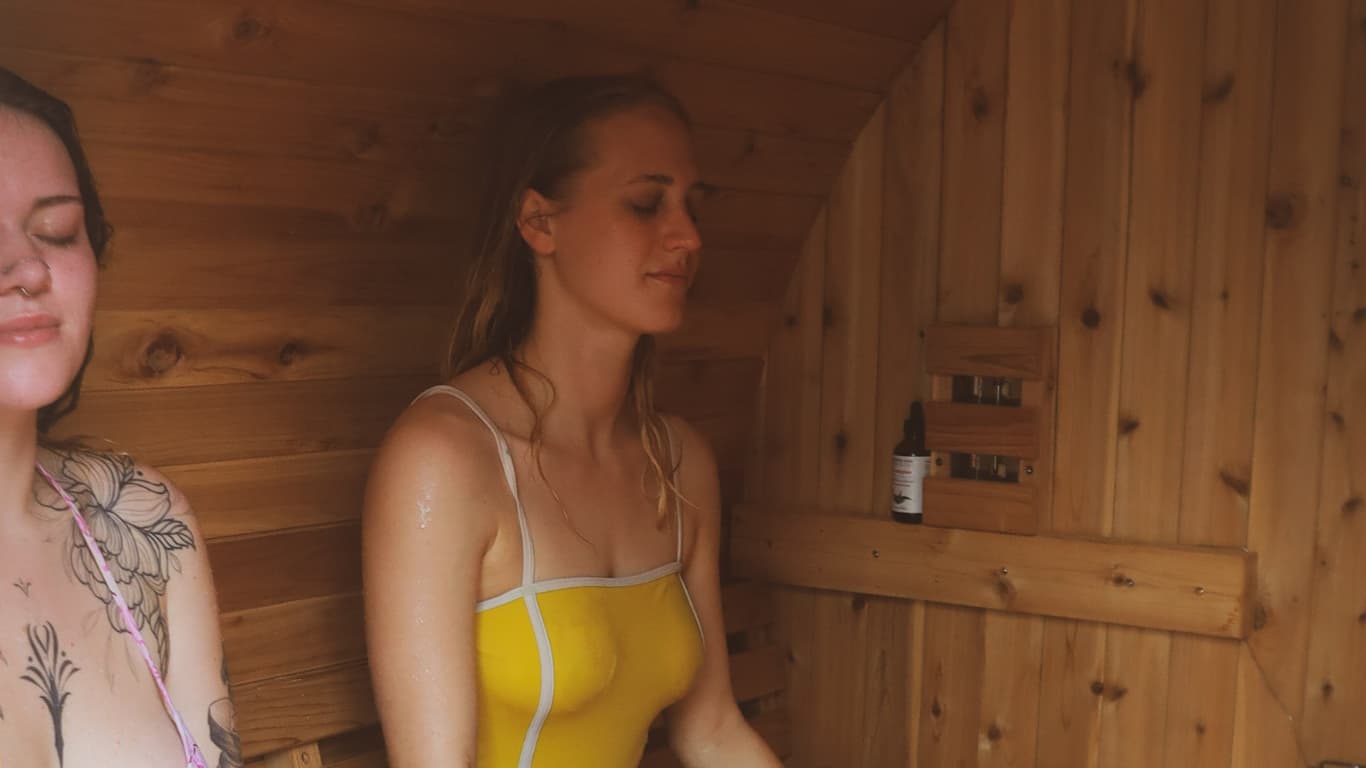 Two guests relaxing inside the wood-fired sauna